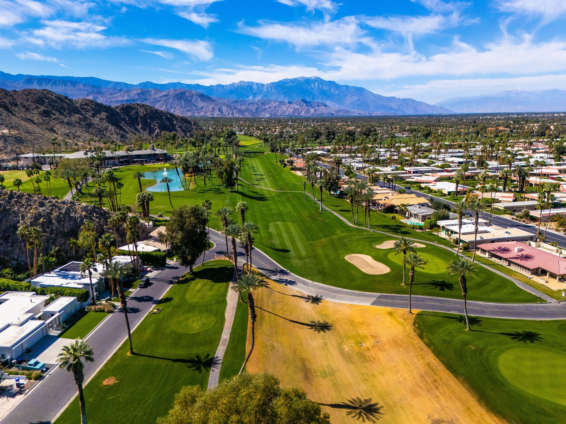 Desert-modern home at 77013 Desi Dr, Indian Wells — photographed for The Chavez Team at The Agency — aerial over the fairways and community toward the mountains