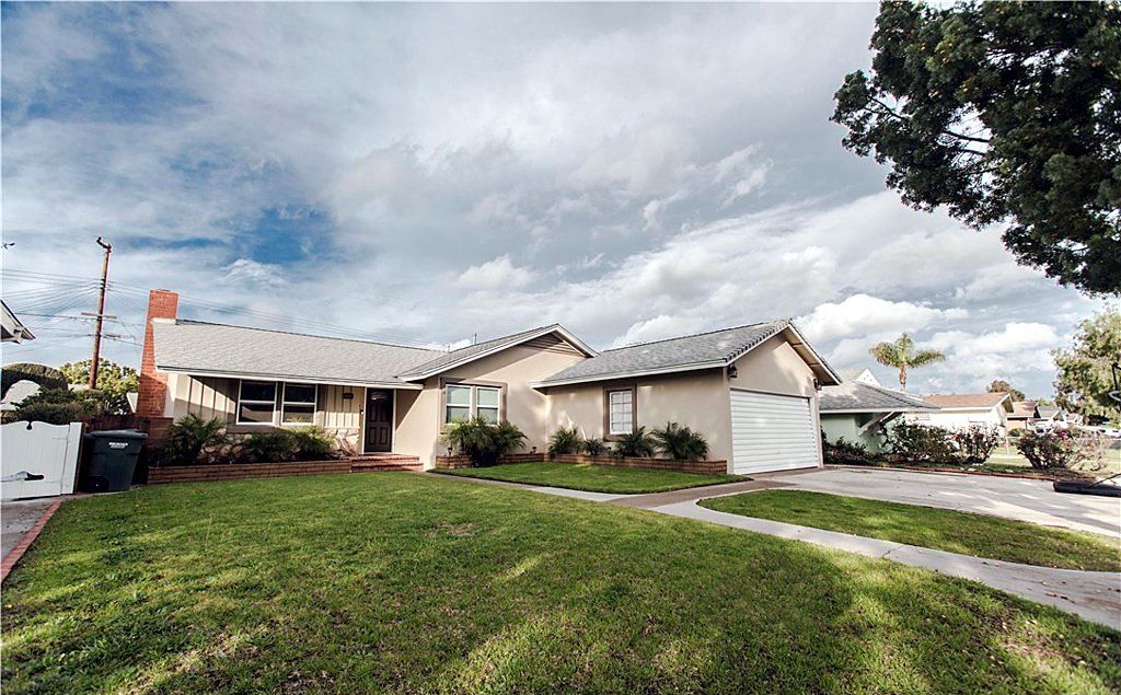 Single-story mid-century home with a brick chimney, attached garage and broad front lawn on San Bruno Drive in Buena Park, California