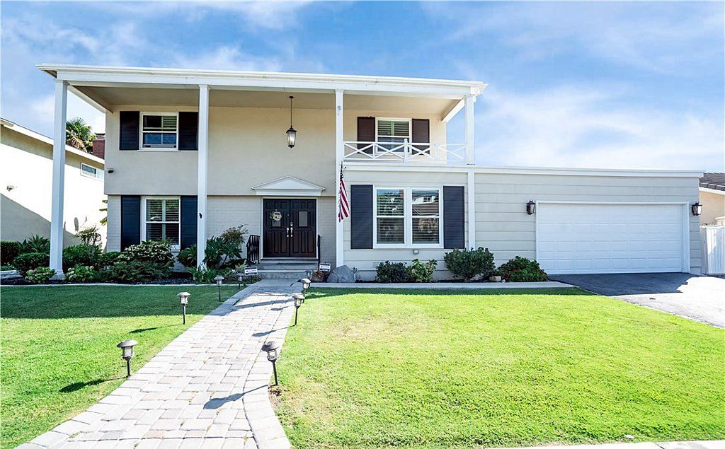 Two-story colonial-style home with a columned balcony, black shutters and a paver walkway on Loma Verde Drive in Fullerton, California
