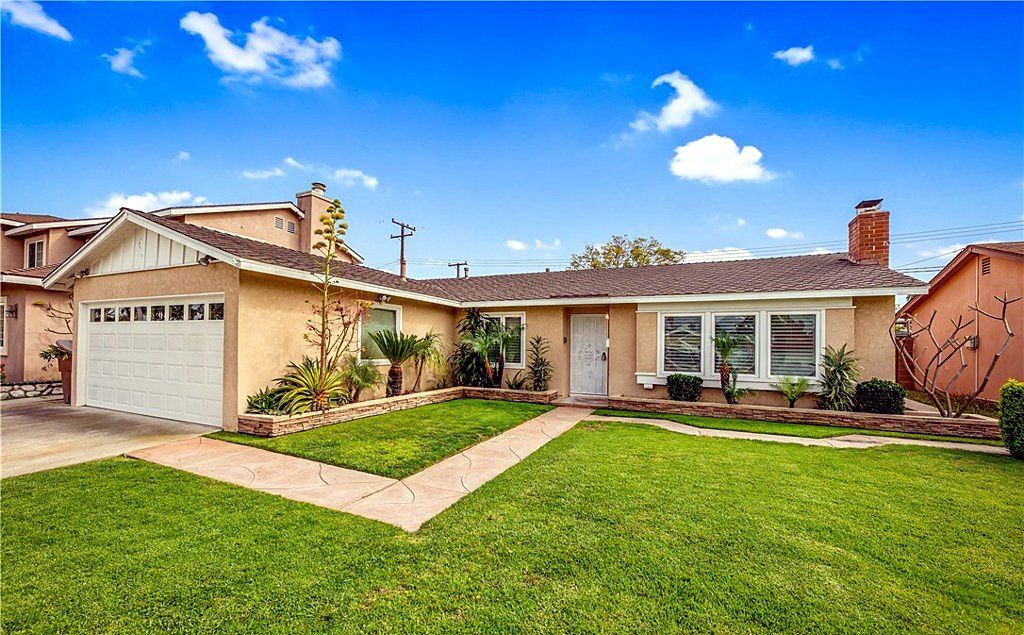 Single-story tract home with a brick chimney, white garage door and a broad green lawn on Amy Avenue in Garden Grove, California