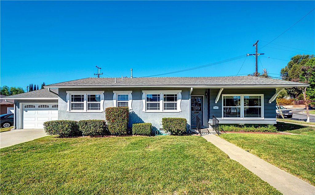 Single-story ranch home with blue-grey siding, white trim and a wide front lawn on South Walnut Street in La Habra, California