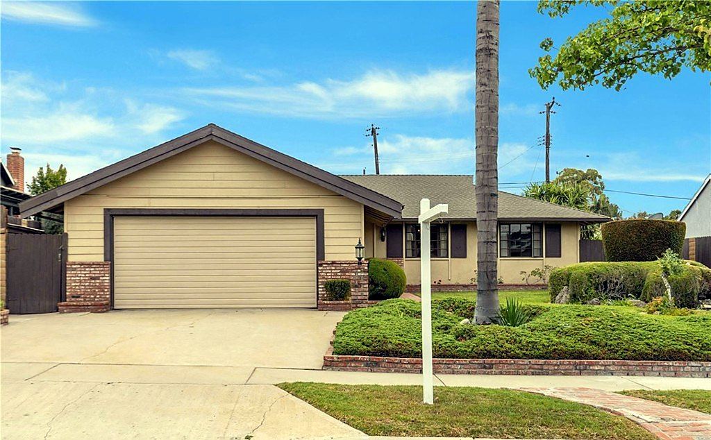 Single-story ranch home with a brick-trimmed garage, dark gable and a palm tree in the front yard on Lorca Road in La Mirada, California
