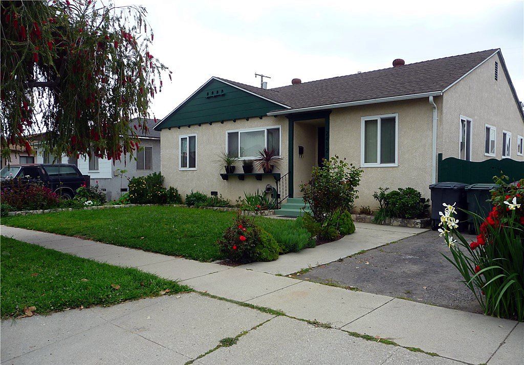 Post-war single-story home with a green gable, front lawn and concrete driveway on Denmead Street in Lakewood, California