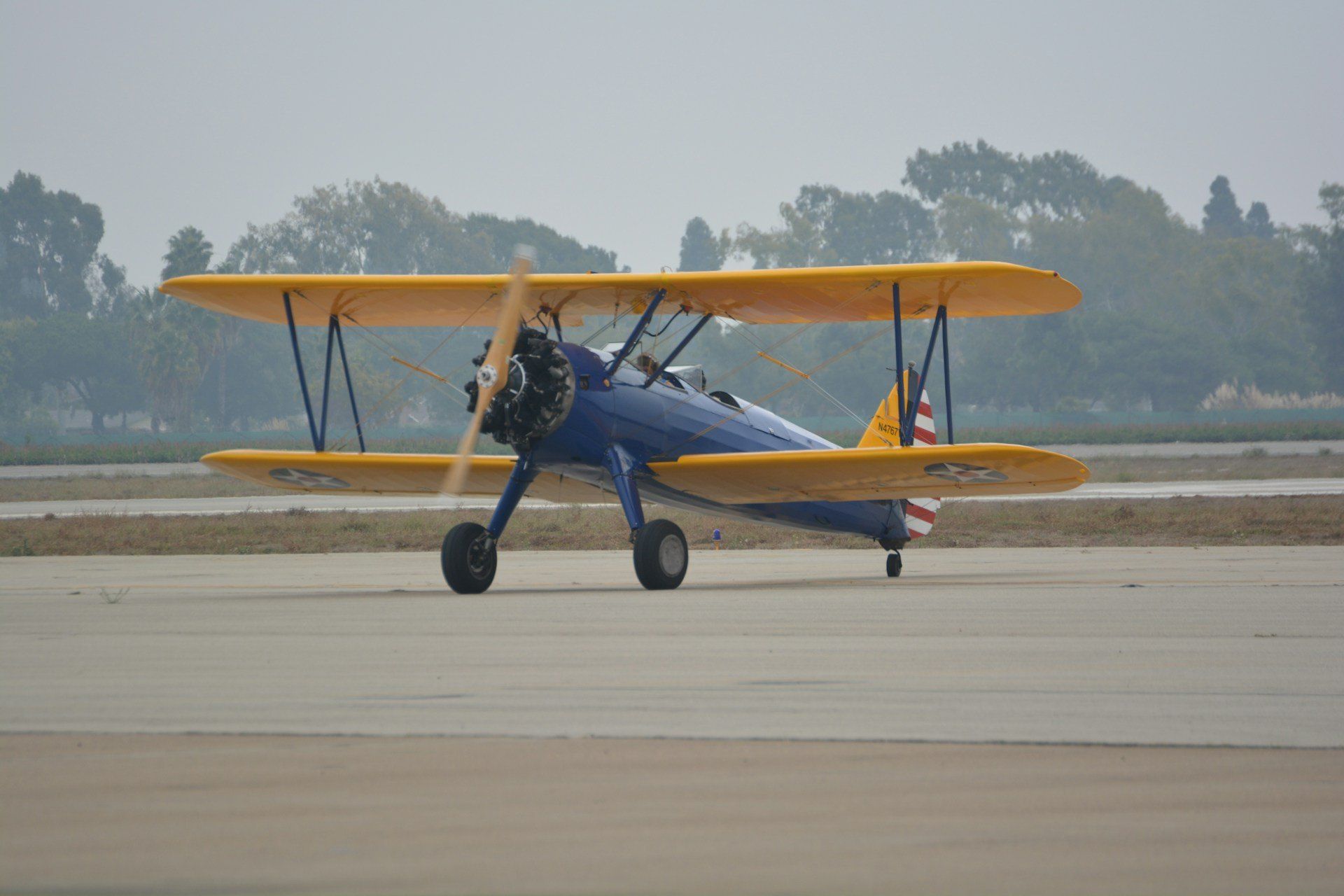 A blue-and-yellow biplane on the runway at the Joint Forces Training Base air show in Los Alamitos