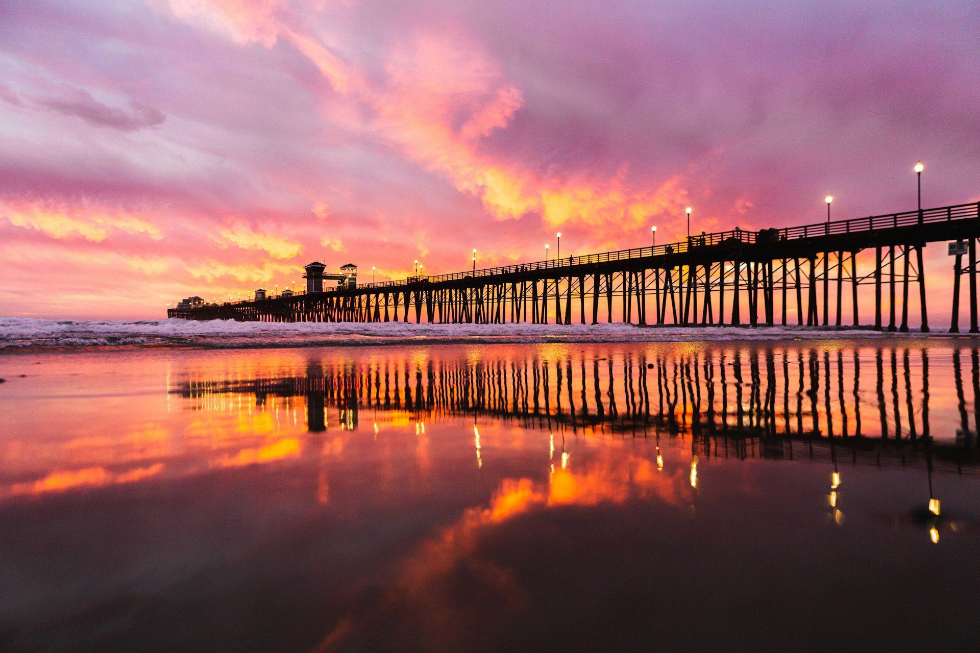 The wooden Oceanside Pier reaching over the ocean at golden hour in Oceanside, California